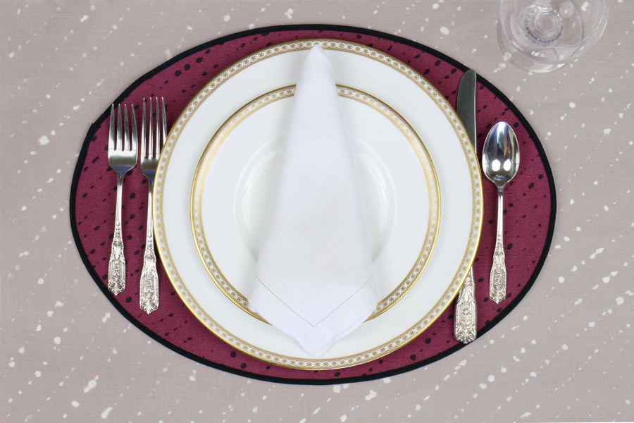 Place setting with 100% linen staccato nero shibori cerise pink placemat on flax shibori linen with white plates