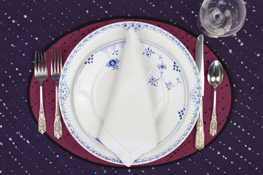 Place setting with 100% linen staccato nero shibori cerise pink placemat on linen with blue & white plates