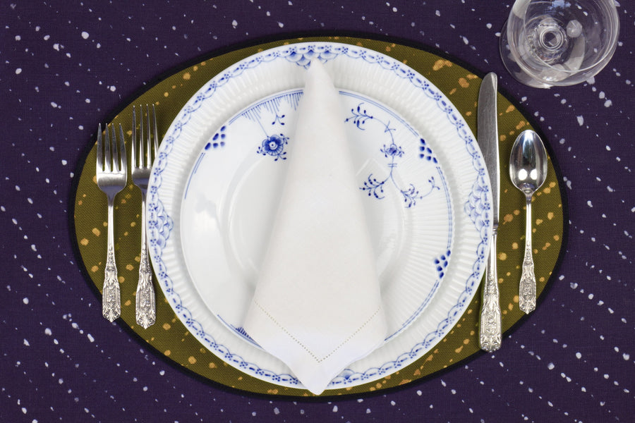 Place setting with 100% linen staccato decolorato shibori fern green placemat on sapphire linen with blue & white plates