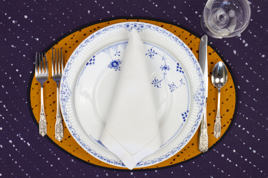 Place setting with 100% linen staccato nero shibori marigold yellow placemat on linen with blue & white plates