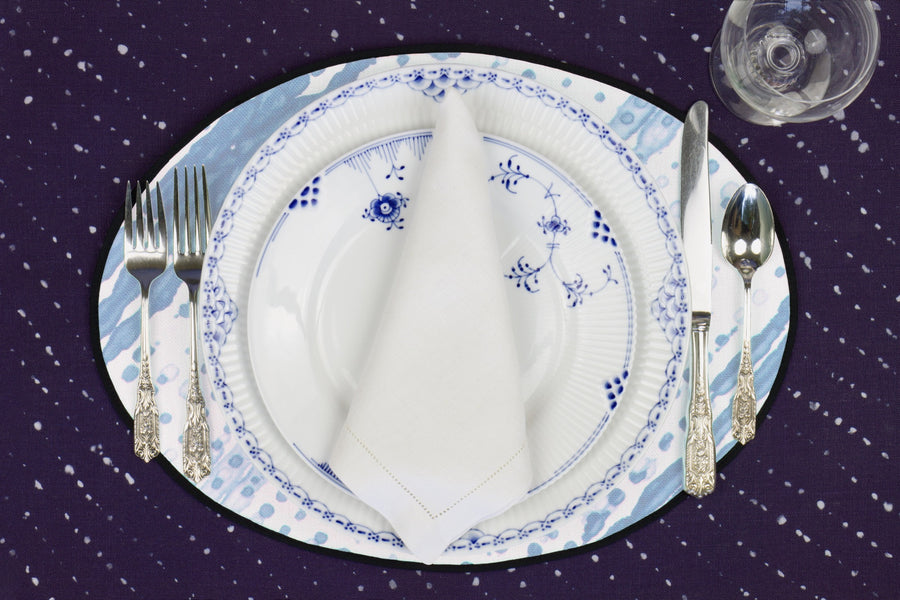 Place setting with 100% linen glissando shibori powder blue placemat on sapphire linen with blue & white plates