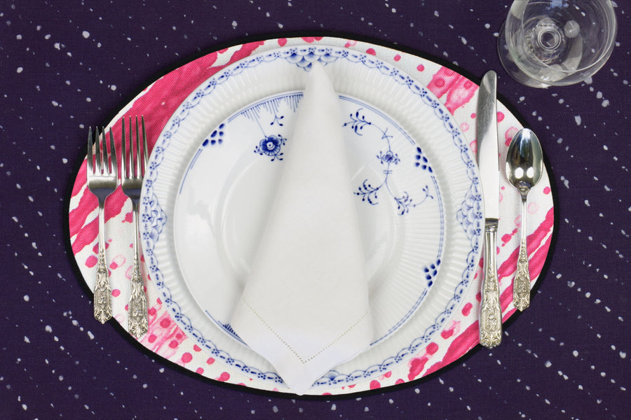 Place setting with 100% linen glissando shibori strawberry pink placemat on sapphire linen with blue & white plates