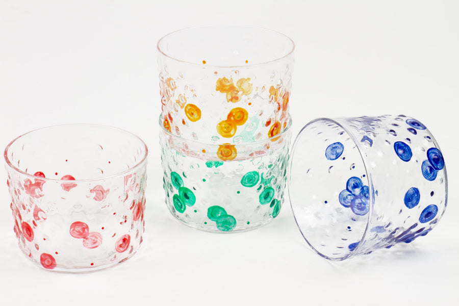 Set of four hand-painted glasses stacked and scattered in tangerine orange, lapis blue, tomato red, and green shamrock