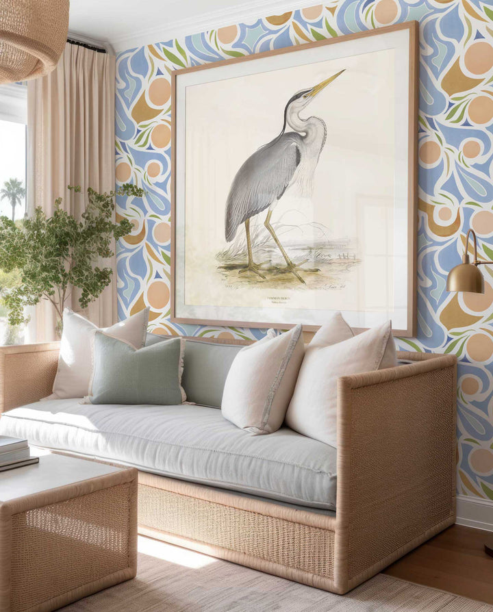 Venable Moore Capri Clay Coated Wallpaper in Peach, Tan, and Light blue in a coastal living room with a large pelican print on the wall and rattan light blue sofa with pillows 