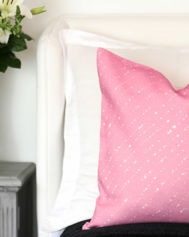 Venable Moore made to order Staccato Sbiancato shibori linen pillow in carnation pink on bed with white linens, dark coverlet, and flowers on bedside table