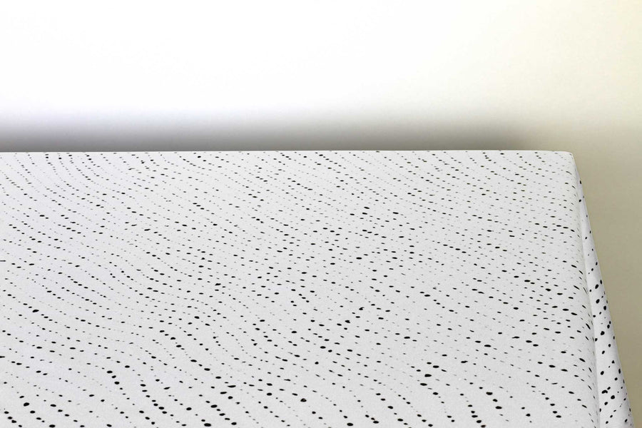 Staccato Nero shibori 100% cotton tablecloth in creamy alabaster white on table corner view against a white background