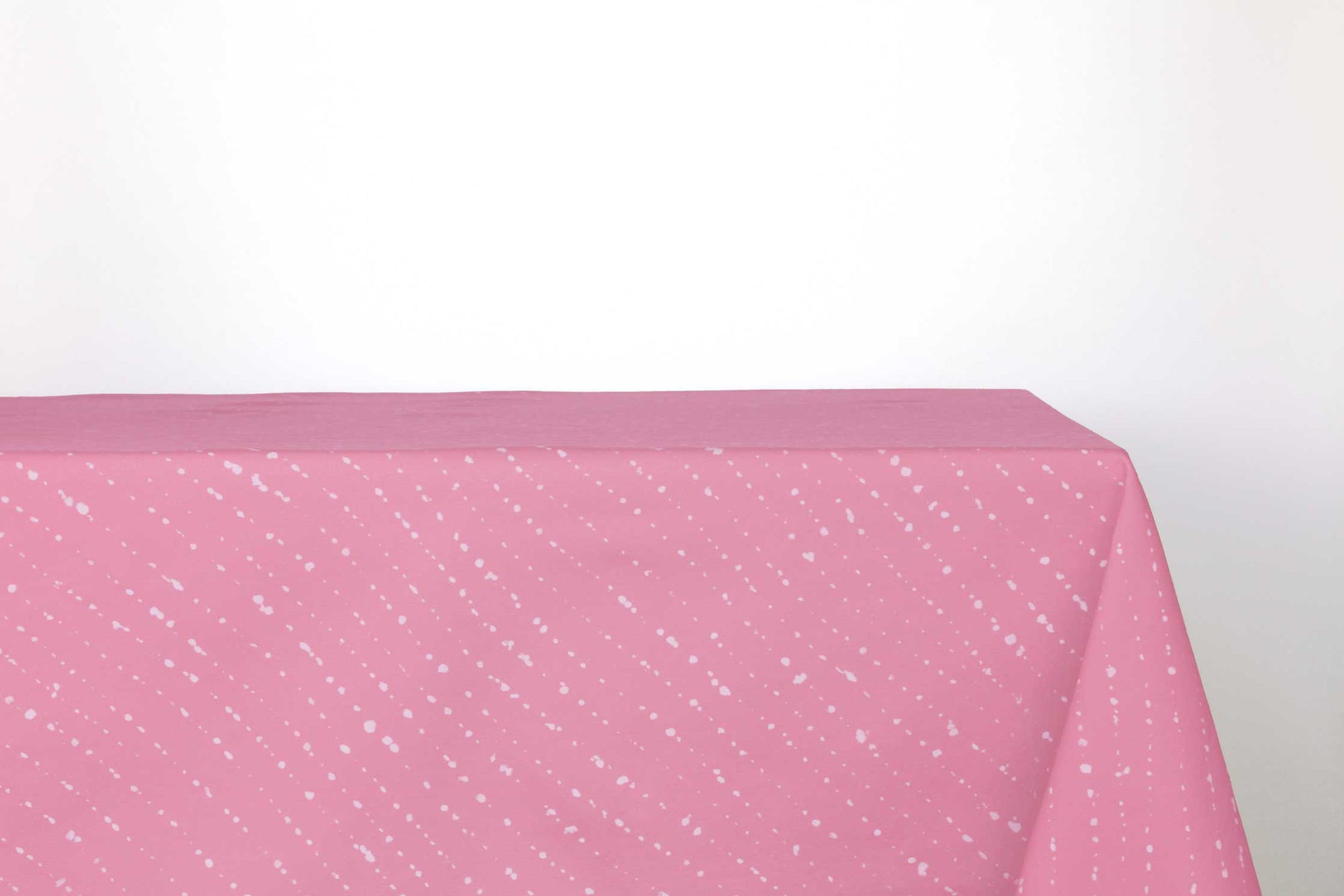 Staccato sbiancato shibori 100% cotton tablecloth in fresh carnation pink on table against a white background 