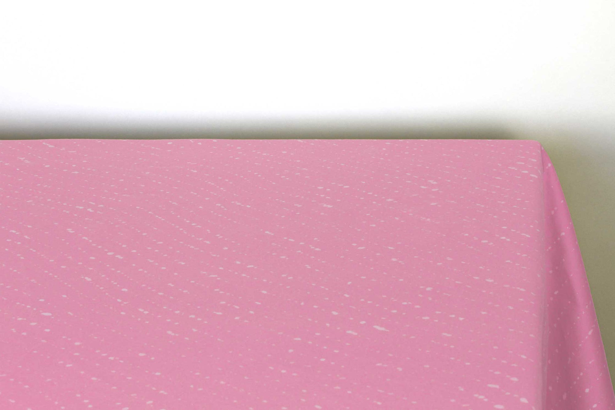 Staccato sbiancato shibori 100% cotton tablecloth in fresh carnation pink on table corner view against a white background 