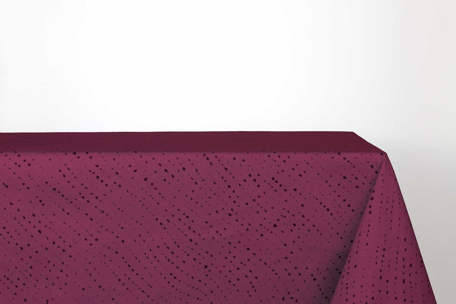 Staccato Nero shibori 100% cotton tablecloth in deep cerise pink on table against a white background 