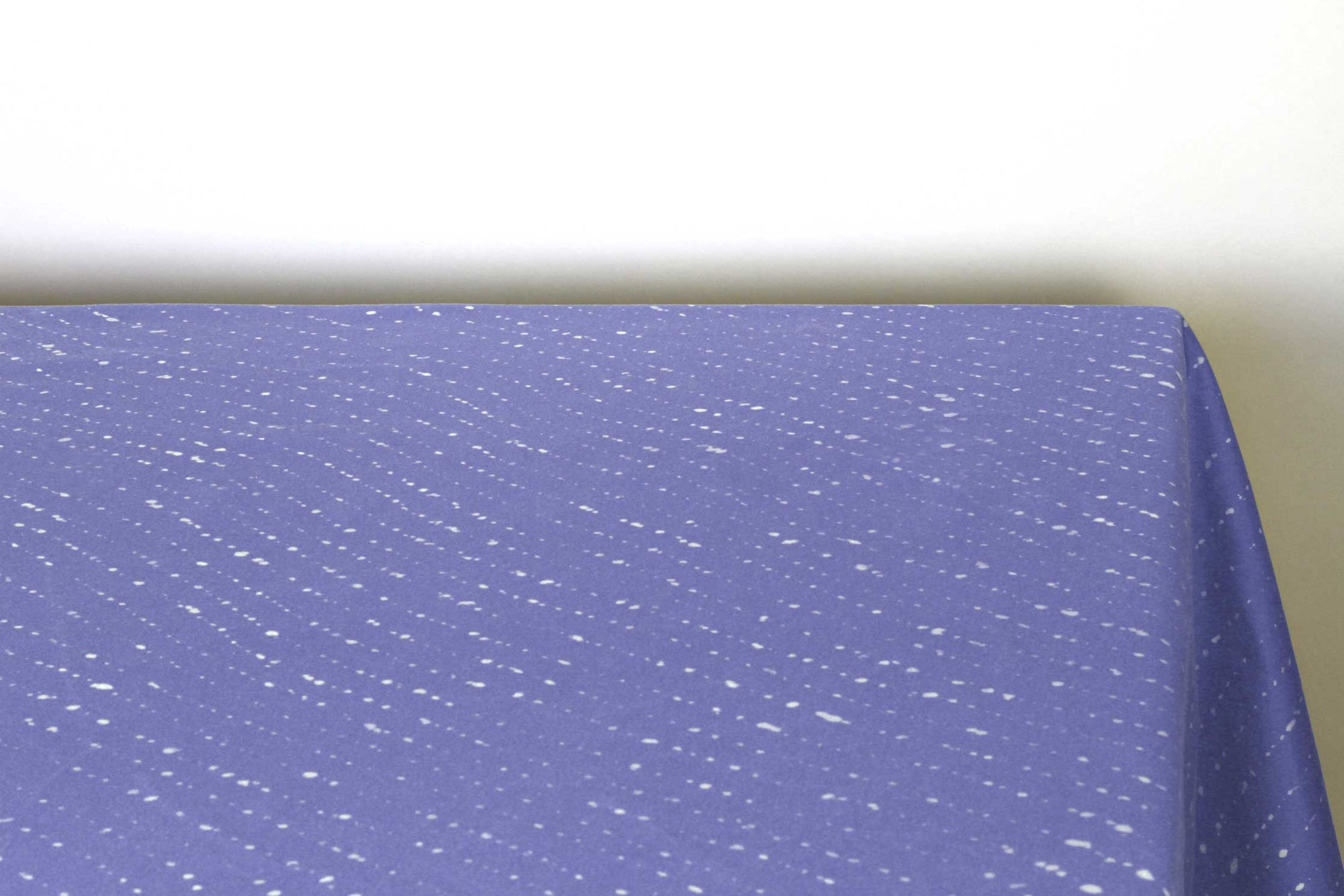 Staccato sbiancato shibori 100% cotton tablecloth in clear cornflower blue on table corner view against a white background 