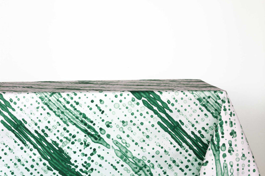 Glissando sbiancato shibori 100% cotton tablecloth in verdant emerald green on table against a white background 