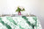 Glissando shibori 100% cotton tablecloth in verdant emerald green on table with full place settings, mosaic garden dinner plates, hand-painted confetti glasses, and a hand-painted vase with roses against a white background 