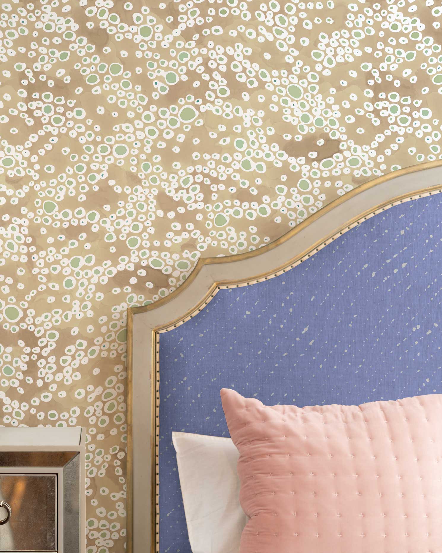 Venable Moore Frizzanted dotted wallpaper in Buff natural on wall in bedroom with Staccato Sbiancato Shibori linen in cornflower blue on headboard with pink pillow and mirrored bedside table