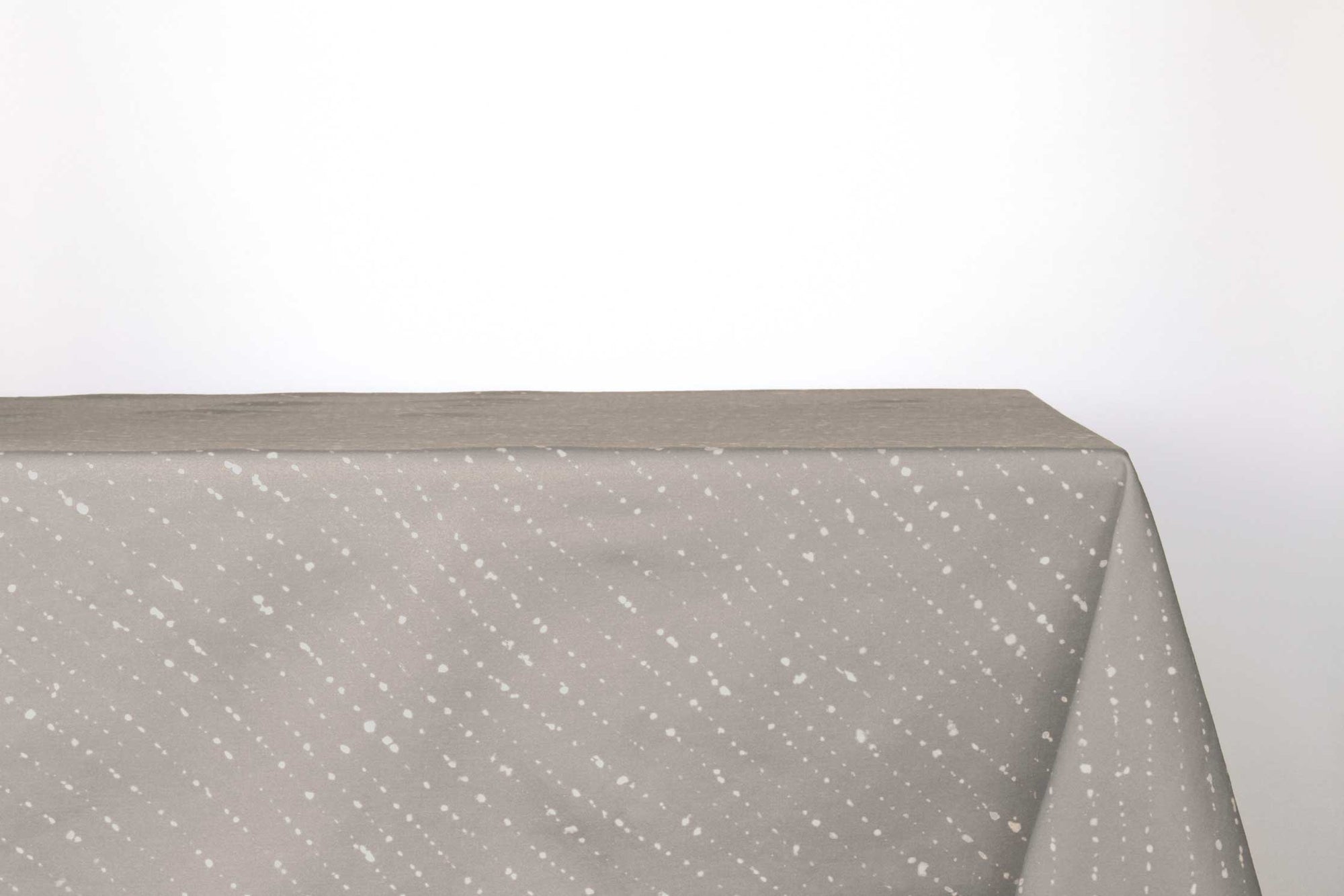 Staccato sbiancato shibori 100% cotton tablecloth in neutral flax tan on table against a white background 