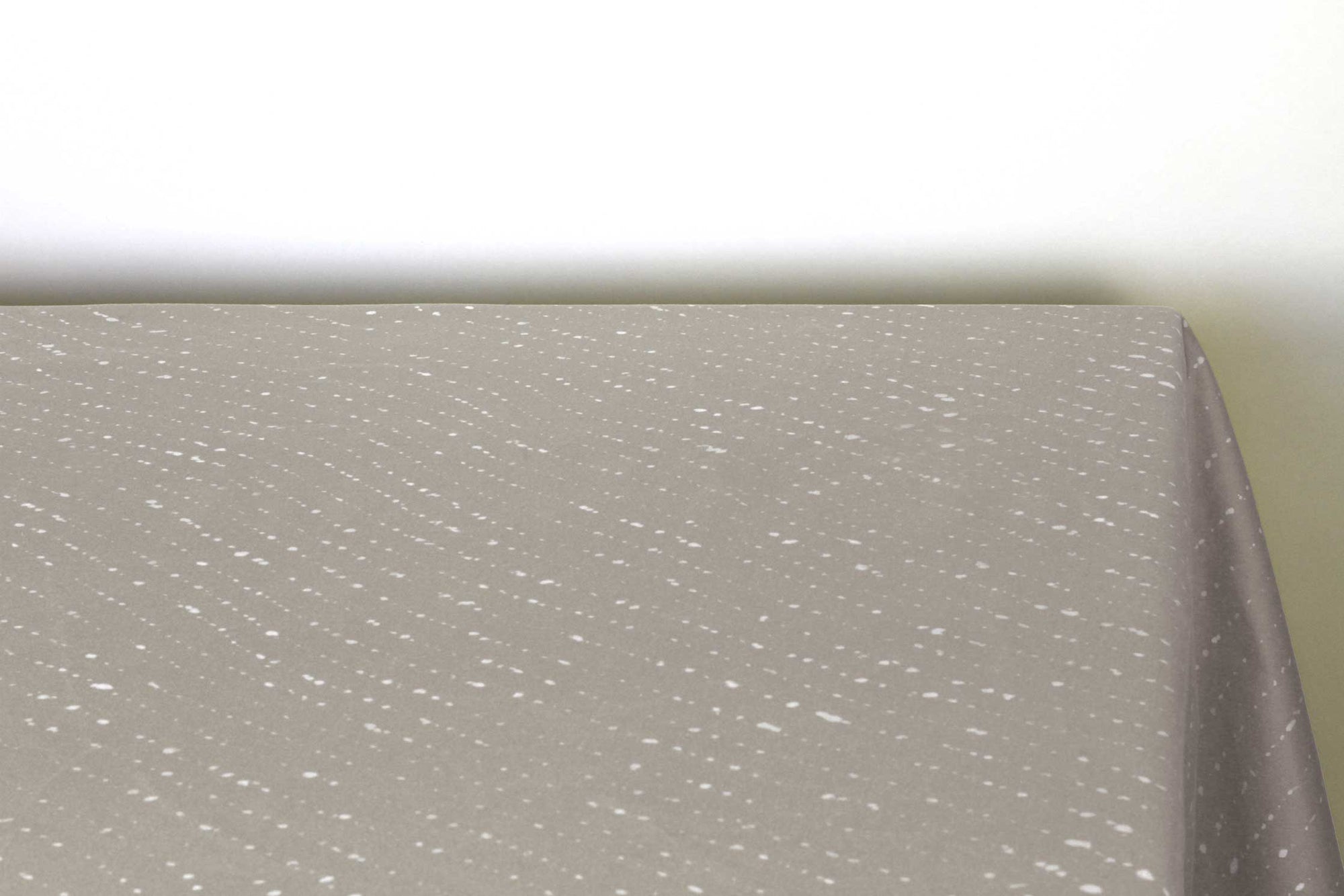 Staccato sbiancato shibori 100% cotton tablecloth in neutral flax tan on table corner view against a white background 