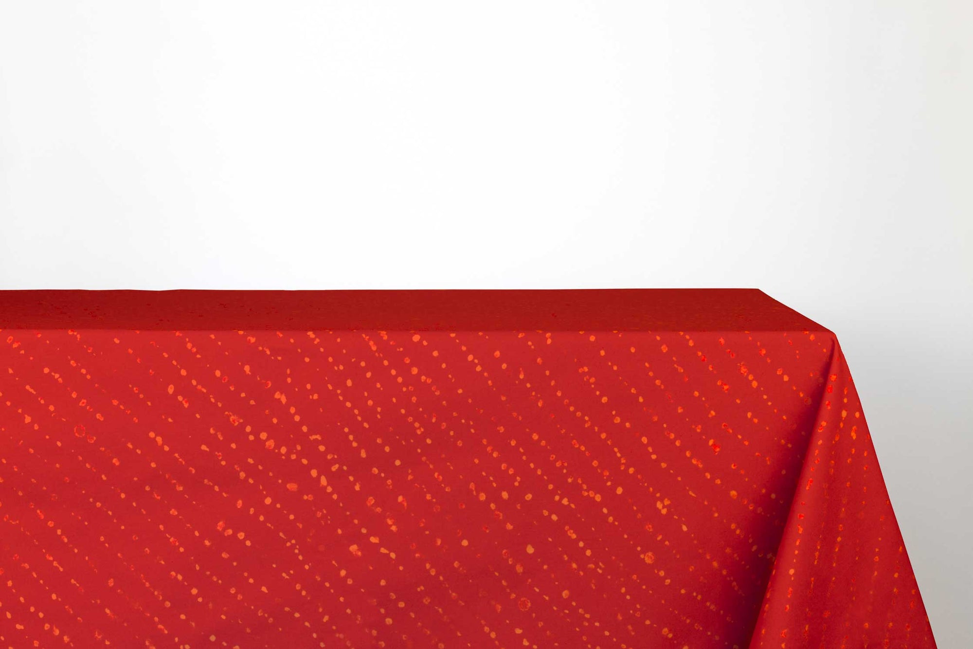Venable Moore Staccato decolorato shibori 100% cotton tablecloth in vibrant paprika red on table against a white background