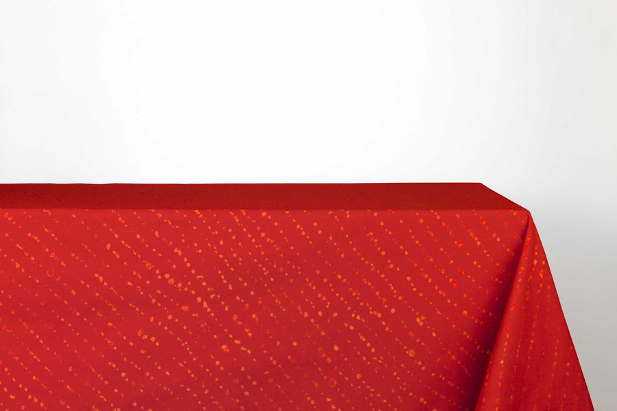 Staccato decolorato shibori 100% cotton tablecloth in vibrant paprika red on table against a white background