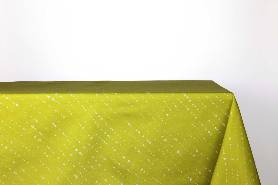 Staccato sbiancato shibori 100% cotton tablecloth in juicy pear green on table against a white background 