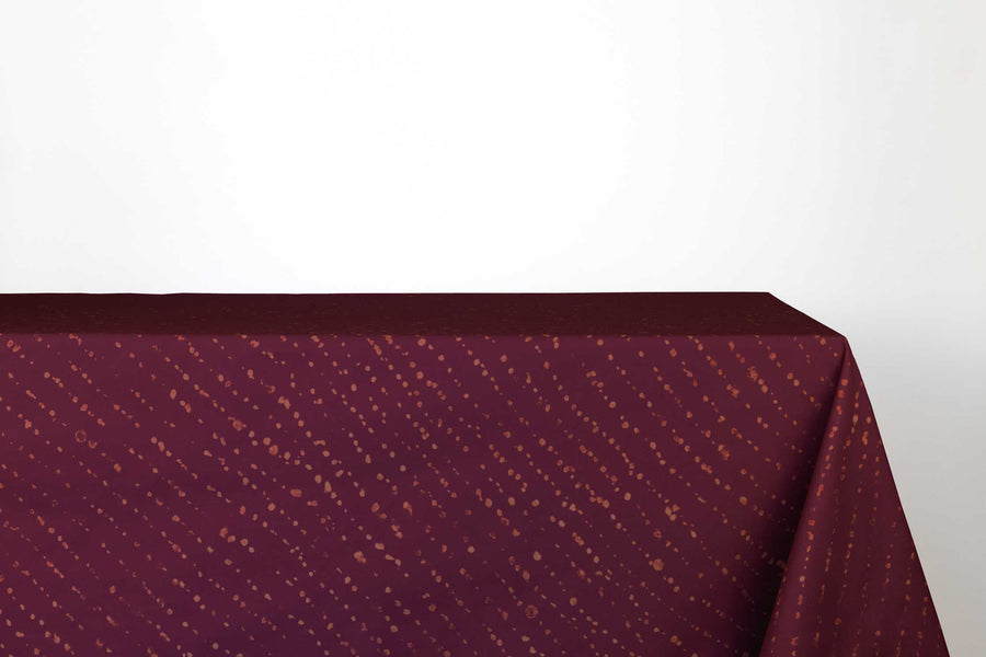 Staccato decolorato shibori 100% cotton tablecloth in saturated plum purple on table against a white background 