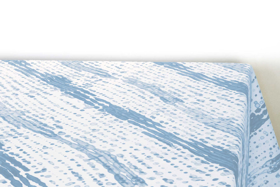 Glissando  shibori 100% cotton tablecloth in soft powder blue on table corner view against a white background
