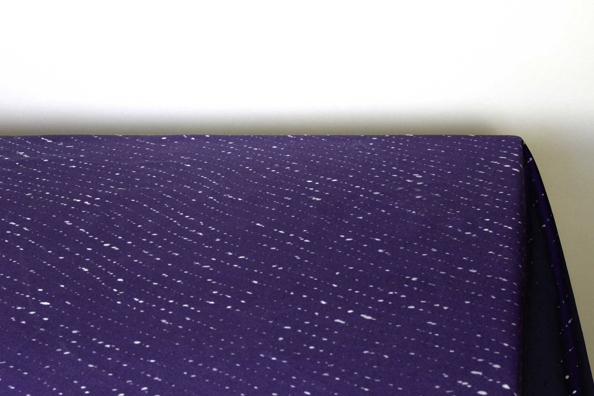 Staccato sbiancato shibori 100% cotton tablecloth in vibrant sapphire blue on table corner view against a white background 