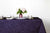 Staccato sbiancato shibori 100% cotton tablecloth in vibrant sapphire blue on table with full place settings, mosaic garden dinner plates, hand-painted confetti glasses, and a hand-painted vase with roses against a white background 