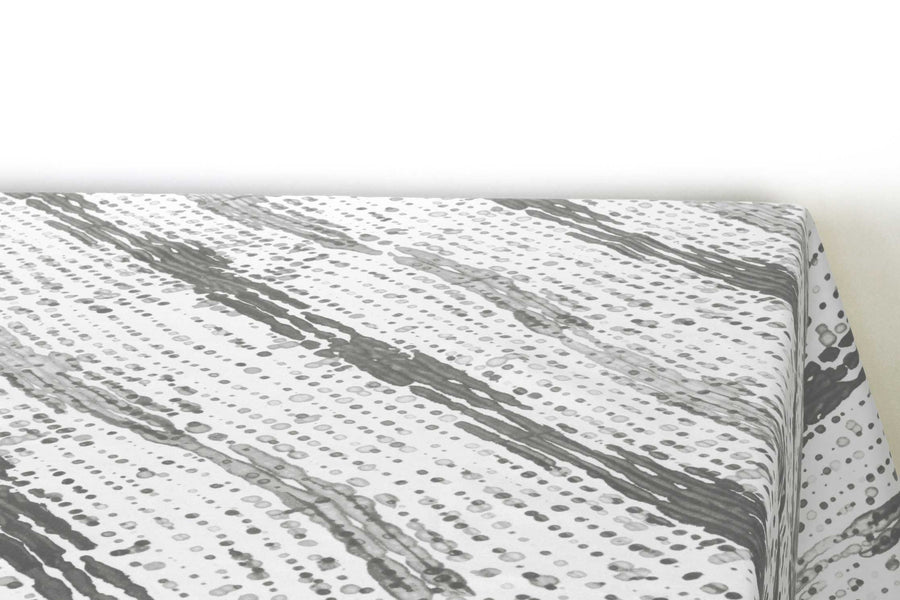 Glissando  shibori 100% cotton tablecloth in neutral storm grey  on table corner view against a white background