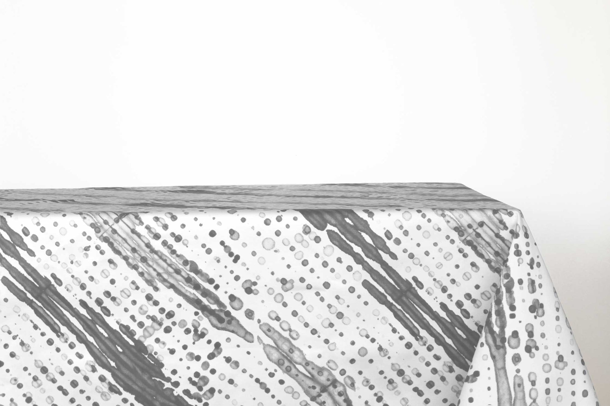 Glissando sbiancato shibori 100% cotton tablecloth in neutral storm grey on table against a white background