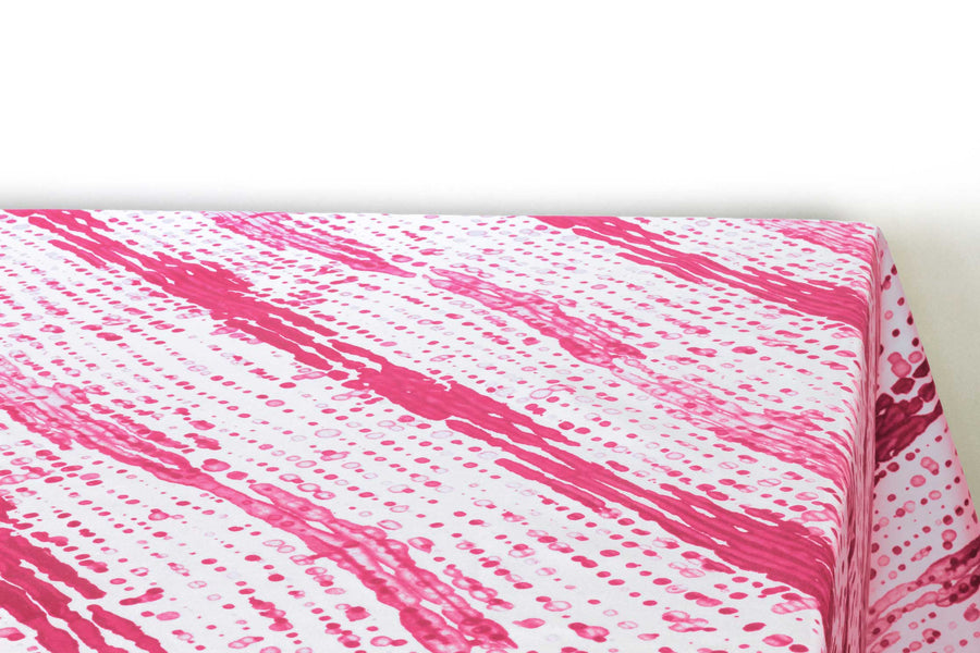 Glissando  shibori 100% cotton tablecloth in juicy strawberry pink on table corner view against a white background