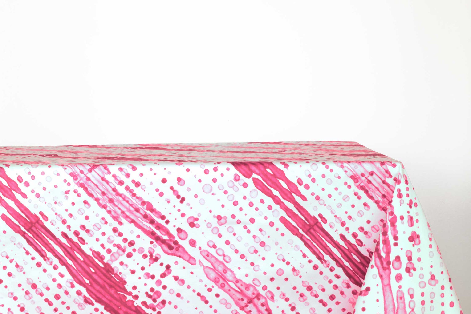Glissando sbiancato shibori 100% cotton tablecloth in juicy strawberry pink on table against a white background 