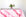 Glissando shibori 100% cotton tablecloth in juicy strawberry pink on table with full place settings, mosaic garden dinner plates, hand-painted confetti glasses, and a hand-painted vase with roses against a white background