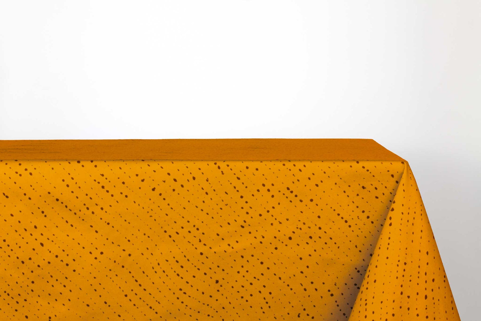 Venable Moore Staccato Nero shibori 100% cotton tablecloth in bold marigold yellow on table against a white background