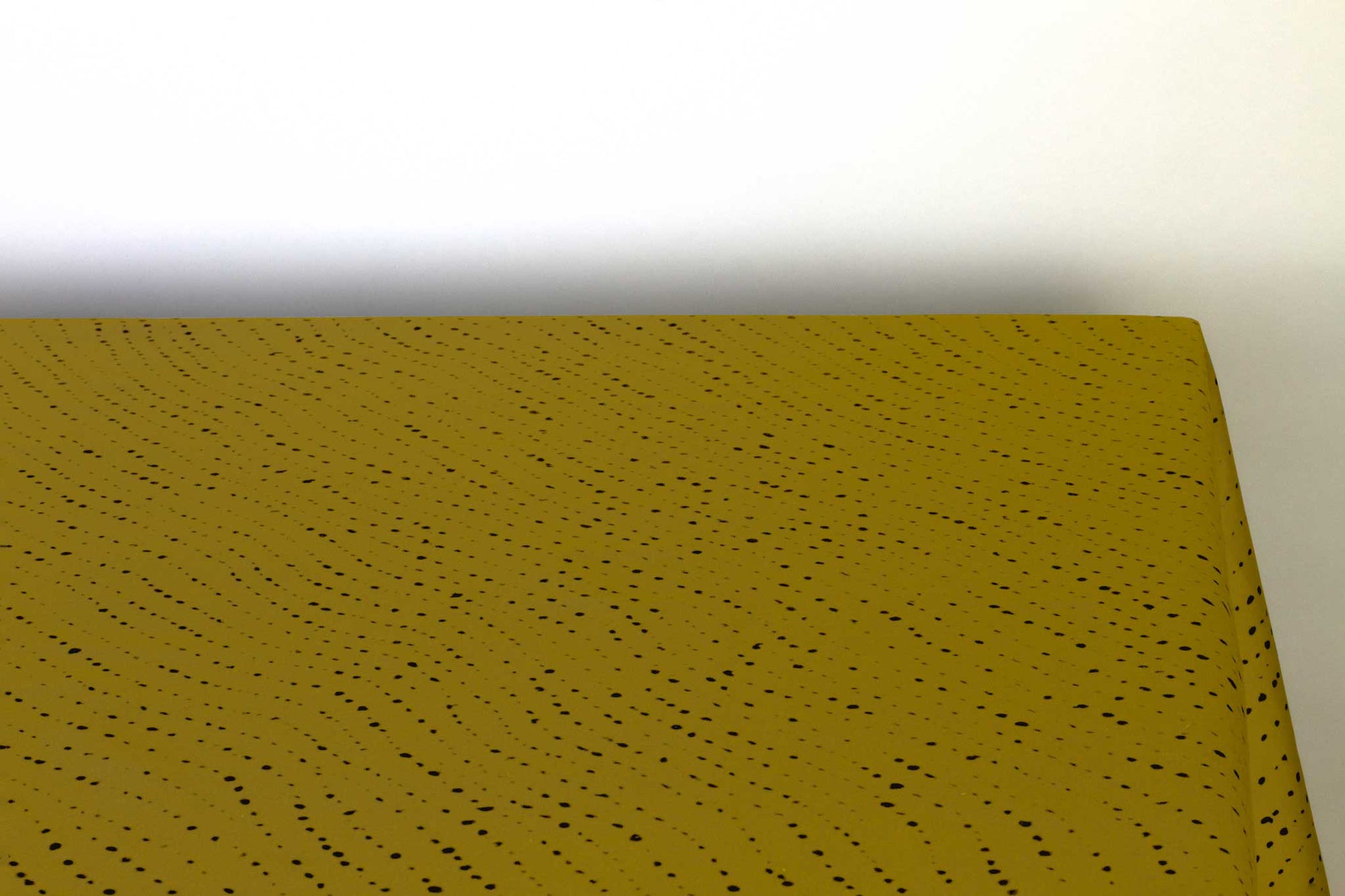 Venable Moore Staccato Nero shibori 100% cotton tablecloth in grouding moss green on table corner view against a white background