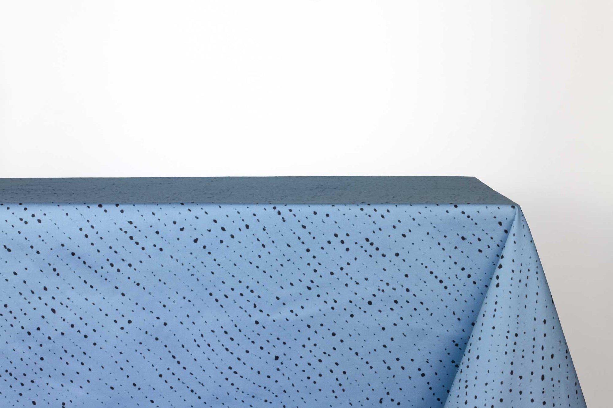 Venable Moore Staccato Nero shibori 100% cotton tablecloth in clear sky blue on table against a white background 