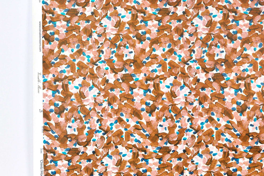 Up close view of Venable Moore Chintz Modern floral abstract in apricot orange, peach, and blue FSC Certified Clay Coated wallpaper roll against a white wall