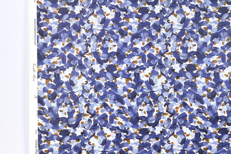 Up close view of Venable Moore Chintz Modern floral abstract in azure blue, orange, and white FSC Certified Clay Coated wallpaper roll against a white wall