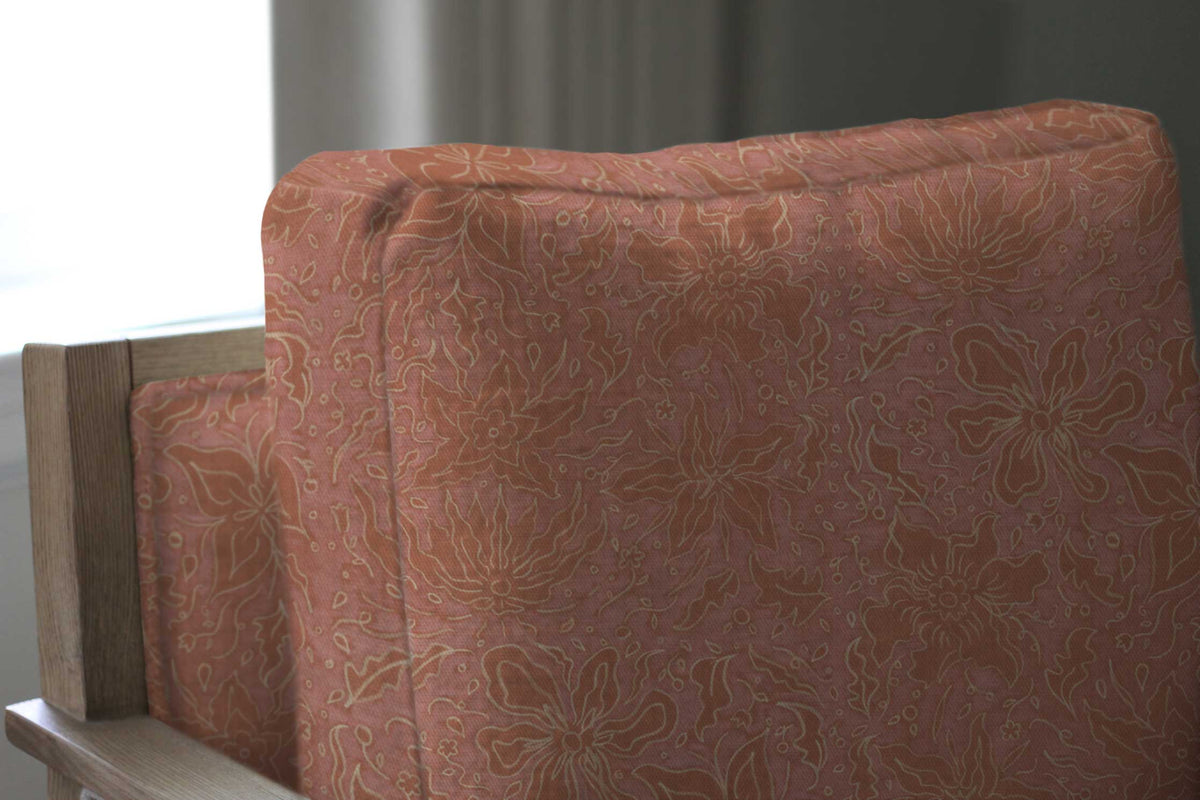 Fiori hand drawn floral cotton fabric in passion fruit pink upholstered on a chair installed in a living room