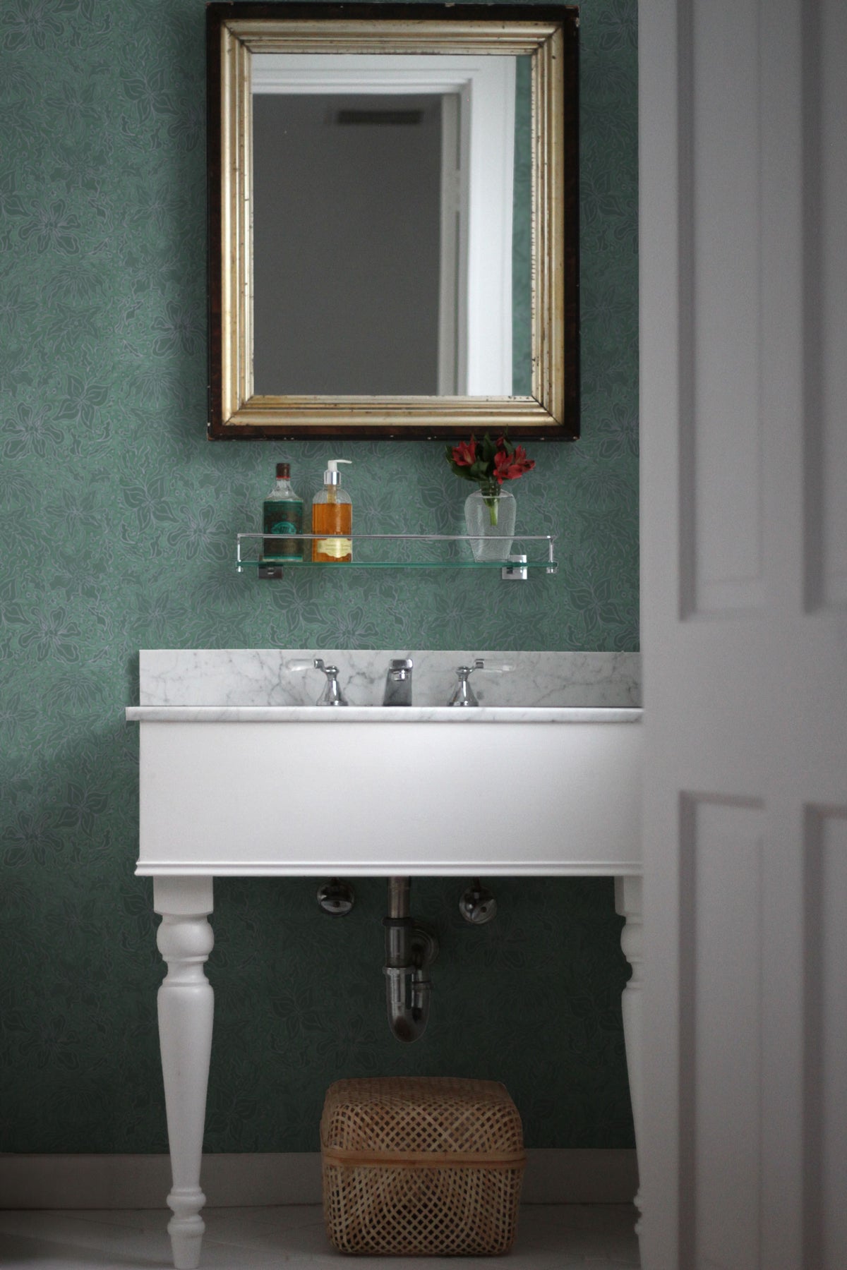 Fiori floral wallpaper in teal installed in a bathroom with mirror and marble topped vanity