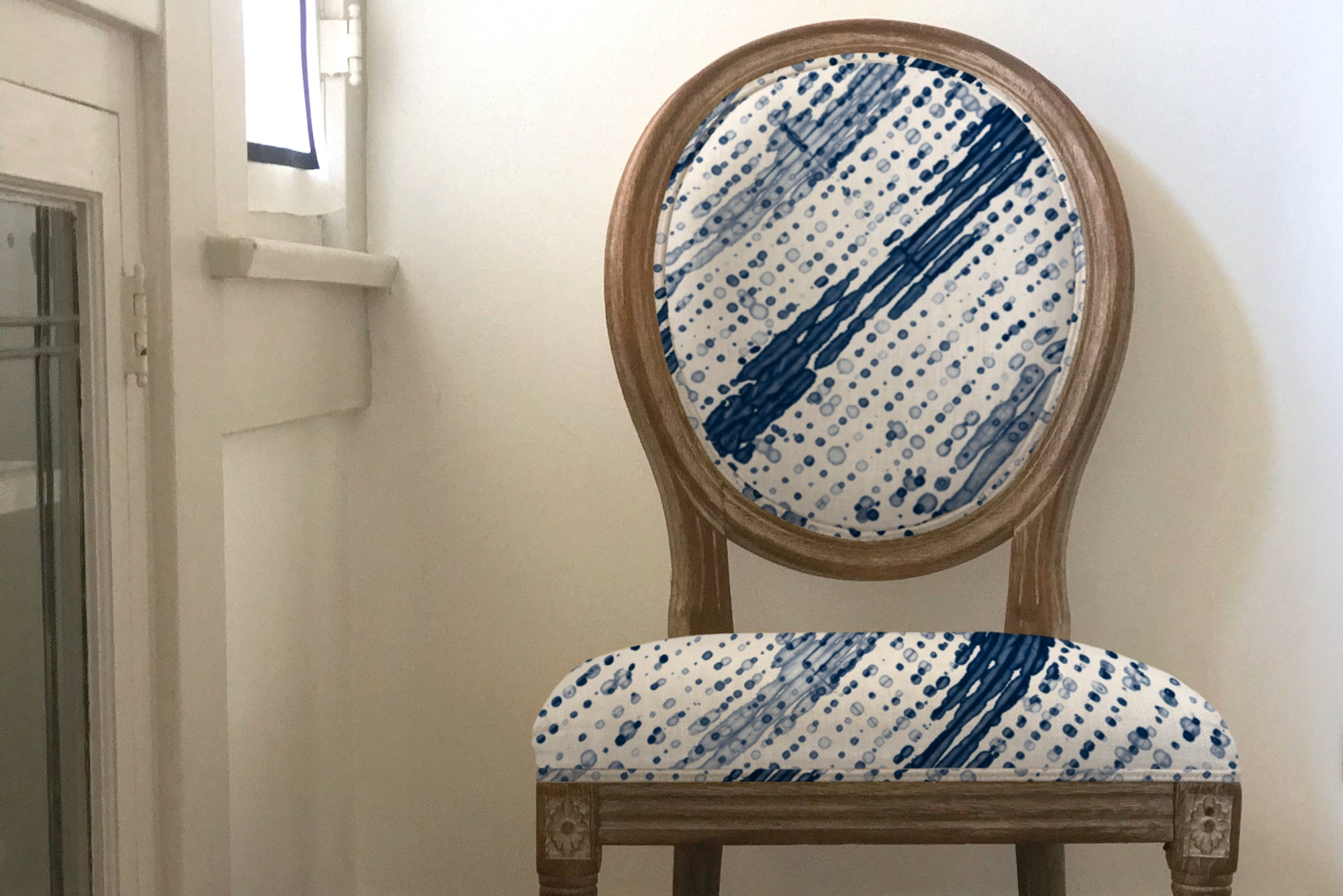 Marine Glissando Shibori linen upholstered on a french chair agains a white wall