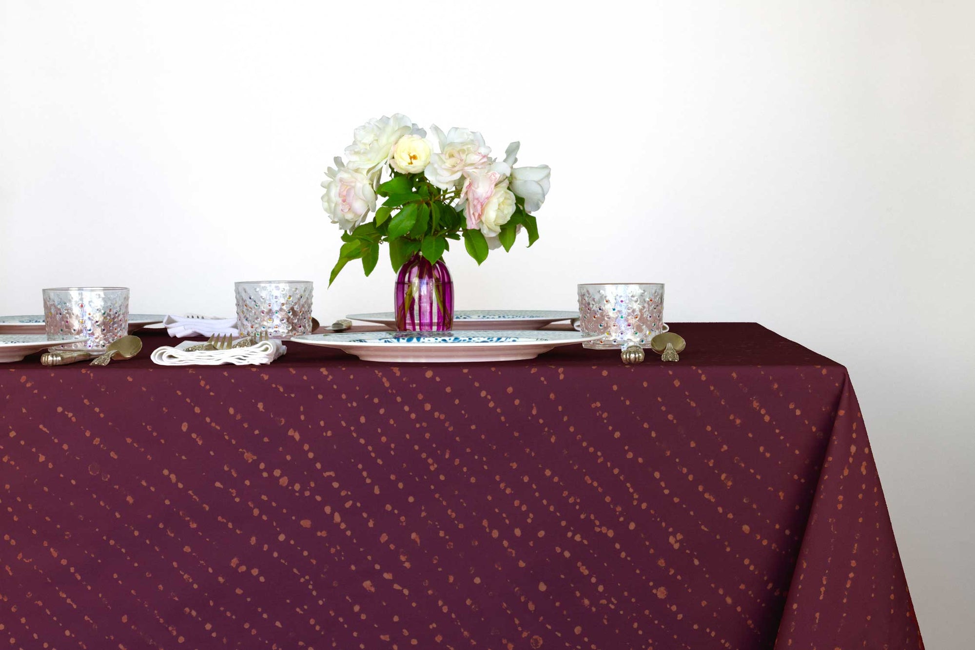 Staccato decolorato shibori 100% cotton tablecloth in plum with mosaic garden dinner plates, hand-painted confetti glaasses and vase with roses 