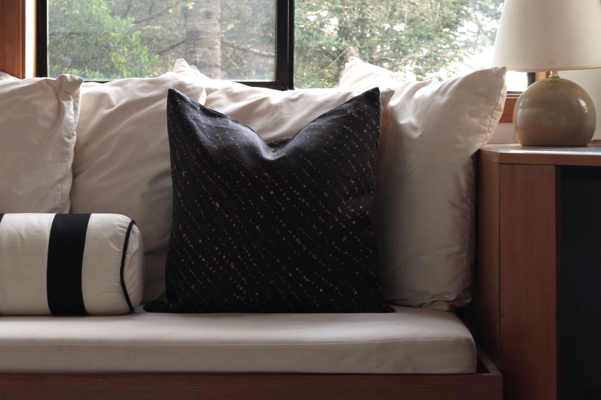 'Staccato Decolorato' Shibori onyx linen pillow on a white built in bench