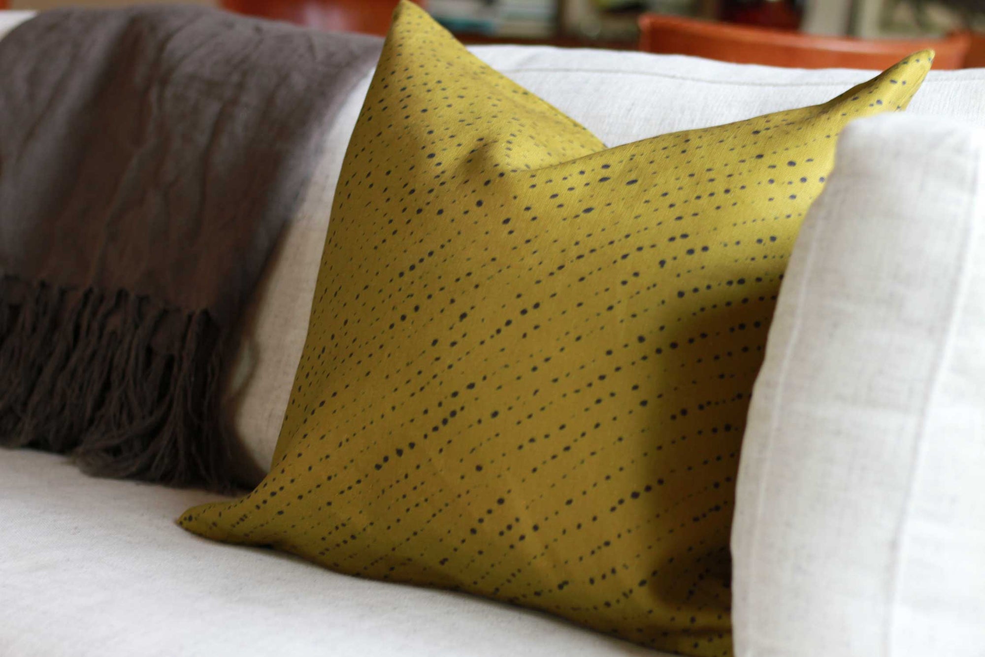 'Staccato Nero' Shibori linen pillow in moss installed on sofa 