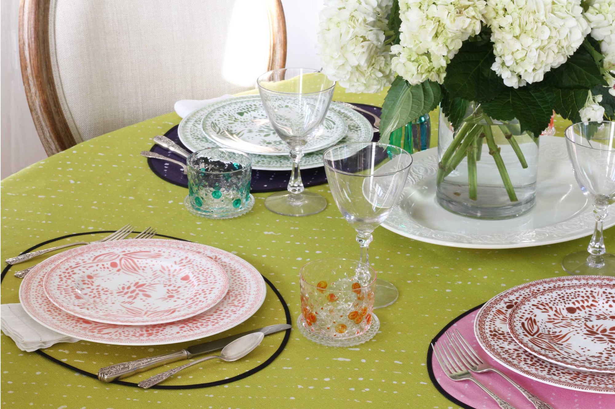 'Staccato Sbiancato' Shibori tablecloth on table with mosaic garden plates, hand-painted glasses, and flowers