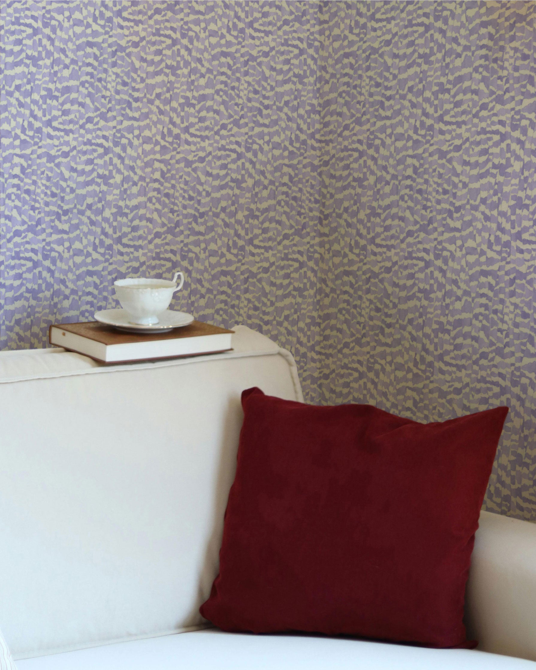 Zebra Stripe animal print wallpaper installed in lavender purple in a living room with a sofa, teacup, and pillow