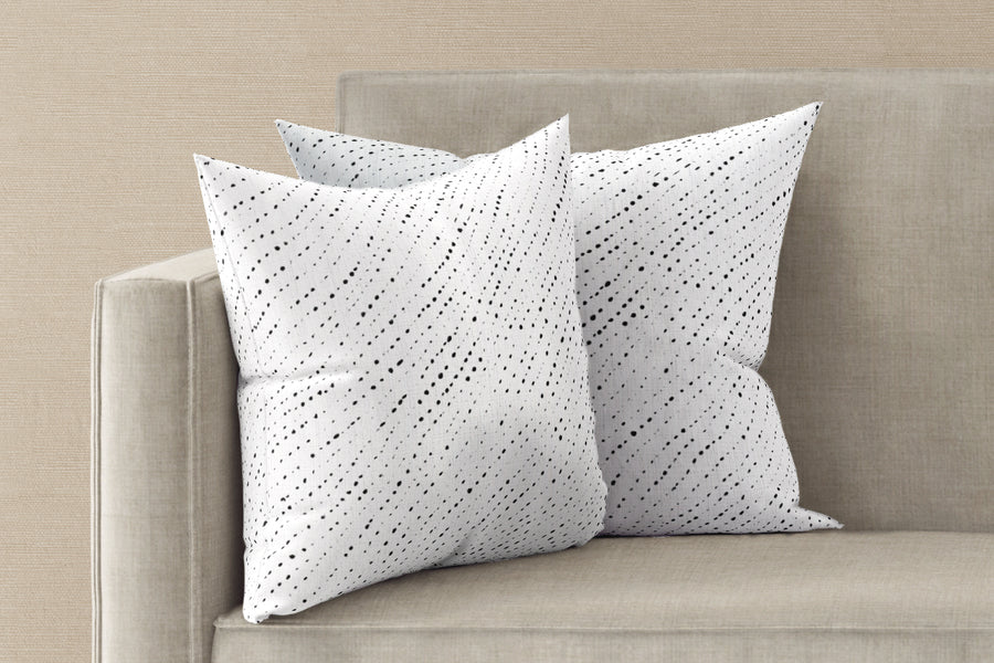 Two 20” x 20” 100% linen reversible staccato nero shibori pillows in alabaster white on a sofa