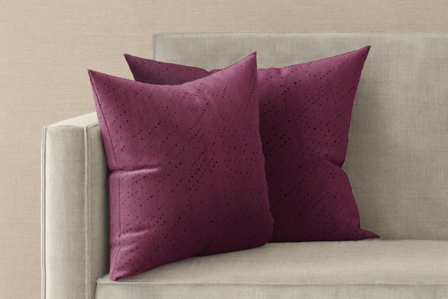 Two 20” x 20” 100% linen reversible nero decolorato shibori pillows in cerise pink on a sofa 