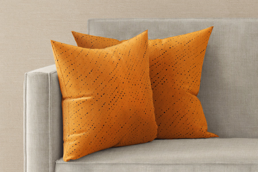 Two 20” x 20” 100% linen reversible staccato nero shibori pillows in marigold yellow on a sofa