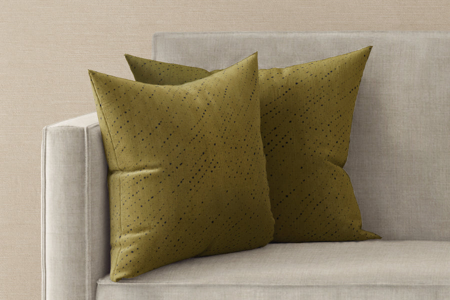 Two 20” x 20” 100% linen reversible staccato nero shibori pillows in moss green on a sofa