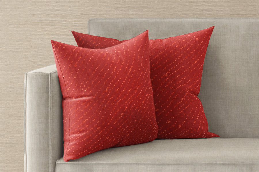 Two 20” x 20” 100% linen reversible staccato decolorato shibori pillows in paprika red on a sofa