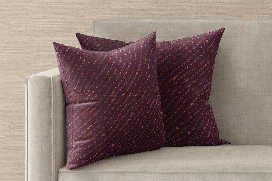 Two 20” x 20” 100% linen reversible staccato decolorato shibori pillows in plum purple on a sofa